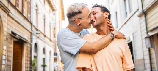 Young gay couple hugging and kissing in city street - Happy homosexual guys celebrating pride day...