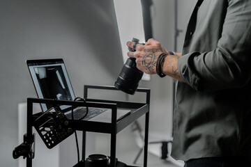 Closeup of the caucasian man photographer holding professional camera at dark photography studio