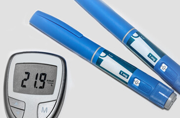 Blood sugar meter with test strips indicates high blood sugar levels and injection pen for...