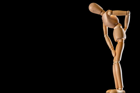 Holzfigur mit gekr&uuml;mmter Wirbels&auml;ule als Symbol f&uuml;r R&uuml;ckenschmerzen mit Textfreiraum auf schwarzem Hintergrund