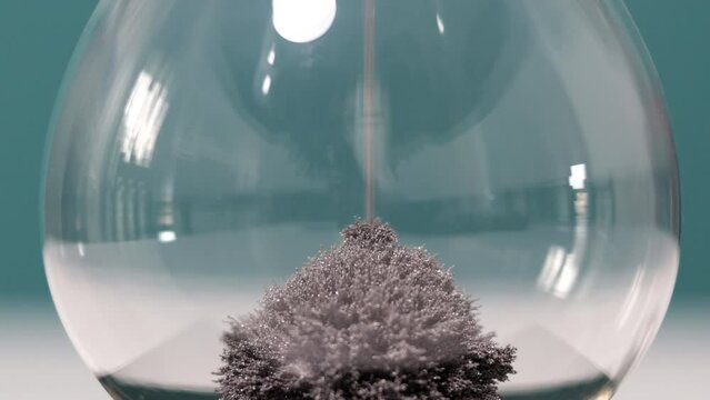 Detail of metal dust falling on the bottom of hourglass magnet. Concept of time passing.