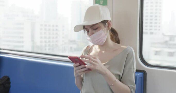 female tourist uses a cell phone while traveling on public transportation to the airport.