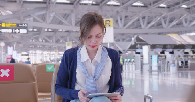 Casual  young woman using her cell phone while waiting to board a plane at the departure gates.