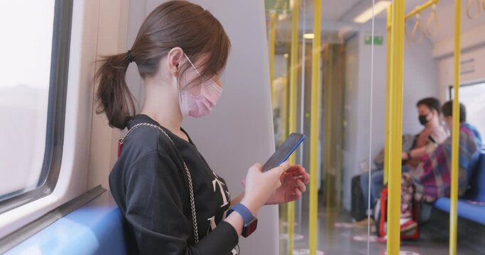 female tourist uses a cell phone while traveling on public transportation to the airport.