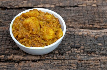 Potato Dahi Curd Curry in a White Bowl Isolated on Textured Wooden Background with Copy Space