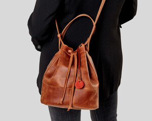 Woman carrying stylish tan leather bucket bag over shoulder © nazarovsergey
