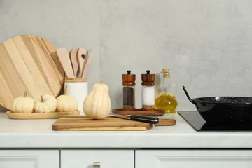 Wooden cutting boards, other cooking utensils and pumpkins on white countertop in kitchen © New Africa