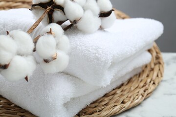 Fototapeta na wymiar Folded terry towels and cotton flowers on white table, closeup