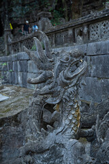 A stone head of a carved dragon at the bottom of the steps of a buddhist temple in Vietnam, south east Asia.