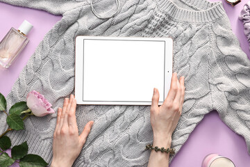 Woman with modern tablet and sweater on violet background, top view. Space for text