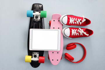 Modern tablet, headphones, skateboards and shoes on light grey background, flat lay. Space for text © New Africa