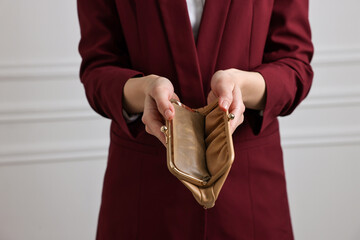 Woman with empty wallet near white wall, closeup