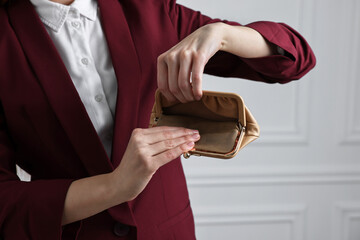 Woman with empty wallet near white wall, closeup