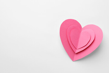 Pink paper hearts on white background, top view. Space for text