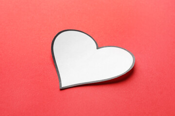 One white paper heart on red background