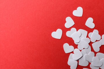 White paper hearts on red background, flat lay. Space for text