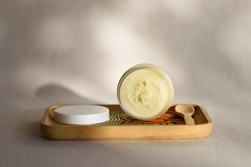 Presentation of shea cream opened in a wooden tray with spoon. Natural cosmetics