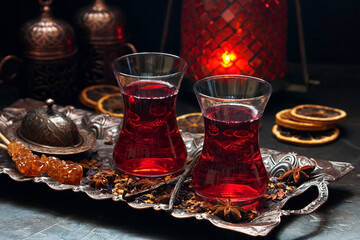 Turkish tea in traditional glasses with spices on dark background