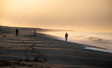 Fototapeta na wymiar Gente na praia ao nascer do sol