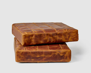 Two stacked functional brown leather square seat cushions on white