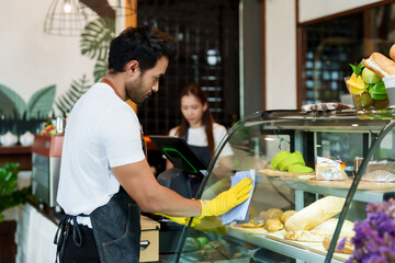 young barista many nationalities cafe owner young businessman Cleaning wiping glass front cake...