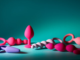 Set of pink anal plug toys over blue turquoise background - obrazy, fototapety, plakaty