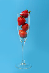 A glass glass full of red ripe strawberries isolated on a blue background. Summer drinks. Summer cocktail. Healthy fruit drinks
