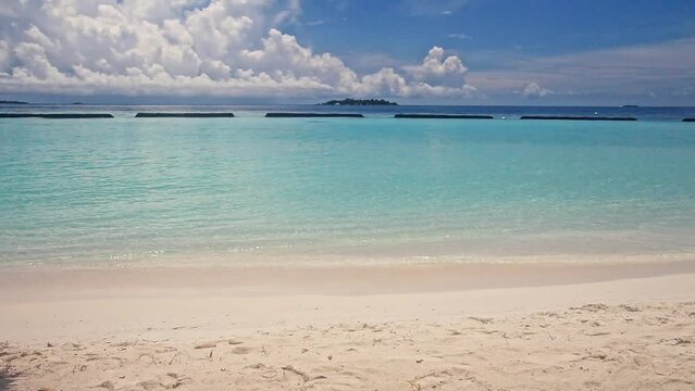 Daylight Serenity: A Summer Vacation at a Maldivian Beach with Turquoise Sea, White Sandy Shore, and Gentle Waves Lapping