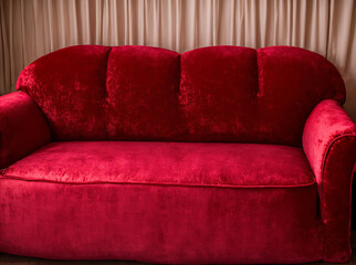 A red velvet couch with a heart shaped pillow on top of it