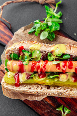 Hot Dog sausage bun, tomato sauce, pickled cucumber, green lettuce leaf takeaway food tasty fresh eating appetizer meal food snack on the table copy space