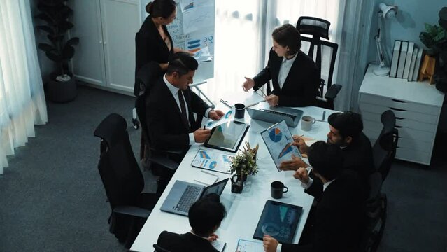 Top view of investor handed financial document to manager while explain marketing idea at meeting table. Diverse people looking at growing graph while listen business team discussion. Directorate.