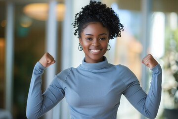 young black woman clenching fists showing off her muscles smiling student raising arms happy radiant face proud of her strength power success achievement victory cheerful indoors joyful earrings