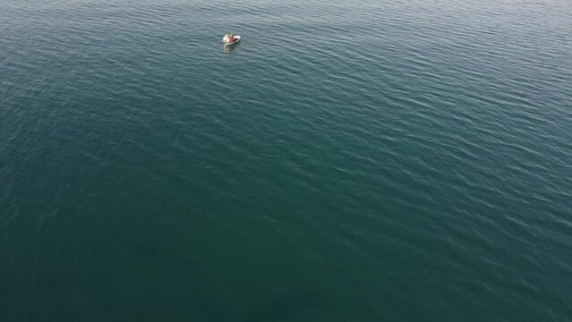 drone: vista su piccola barca bianca con pescatore su mare azzurro.