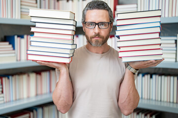 Portrait of funny teacher with book in library classroom. Handsome teacher in university library....