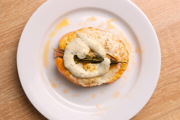 A freshly baked piece of salmon is placed on a plate and sauce is added