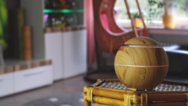 A diffuser distributes flavored water as steam in the living room. Blurred background with copy space. Real time endless loop with zoom.