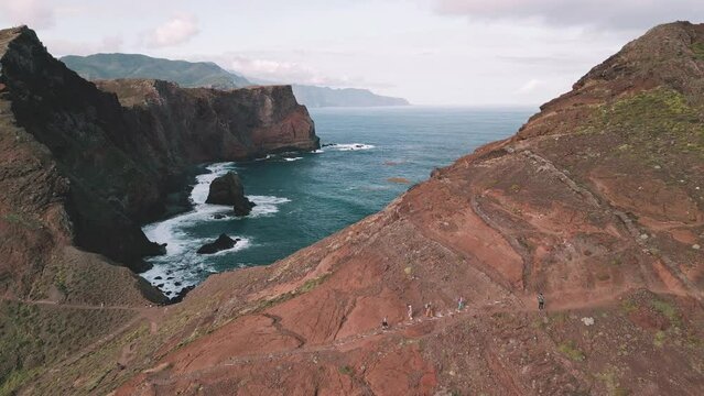 Aerial flight at the spectacular Vereda da Ponta de  Sao Lourenco Hike, Madeira, Portugal. Drone strafing and rotating with unrecognizable hikers in the foreground.