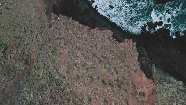Aerial flight at the spectacular Vereda da Ponta de  Sao Lourenco Hike, Madeira, Portugal. Drone flight in top down view tilting up to reveal the rough landscape and cliffs.