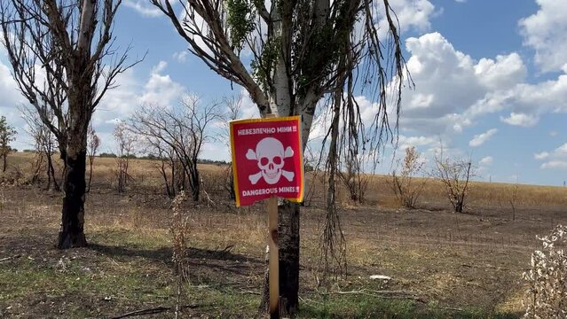 danger sign mine in Ukrainian near an agricultural field during war in Ukraine, translation: "Mine Danger"