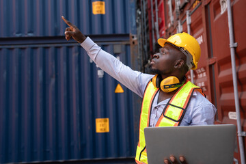 African American foreman holding notebook computer with container background