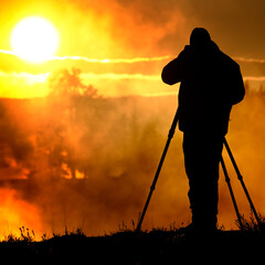 Photographer with Tripod Taking Photographs of Sunrise or Sunset with Steam