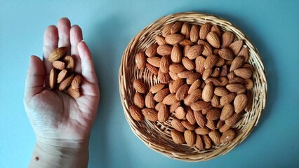 a man holding nuts. a handful of nuts in his hand on a gray background.