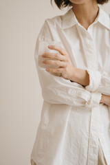 Beautiful woman in white shirt hold glass of water. Aesthetic minimalist healthy lifestyle