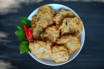 Corn Fritters with Corn. Healthy and Diet Food . Crispy fried corn ball in a white plate on wooden table, Vegetarian food, Thai food, snacks Thai style. Zucchini fritters or vegetarian zucchini pancak