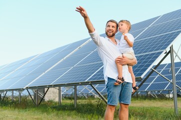 Man showing little child the solar panels during sunny day. Father presenting to his kid modern energy resource. Little steps to alternative energy.