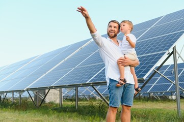 Man showing little child the solar panels during sunny day. Father presenting to his kid modern...