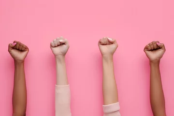 Foto op Canvas Raised fists of women on a pink background, girl power © Alina