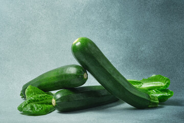 Fresh Green Zucchinis with Romaine Lettuce on a Textured Grey Surface