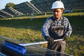 Indian handyman cleaning solar panels form dust and dirt