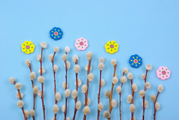 Easter decoration with pussywillow twigs and wooden painted flowers on blue background for greeting card or poster